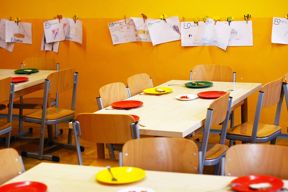 kindergarten classroom with plates on tables and papers hanging on the wall