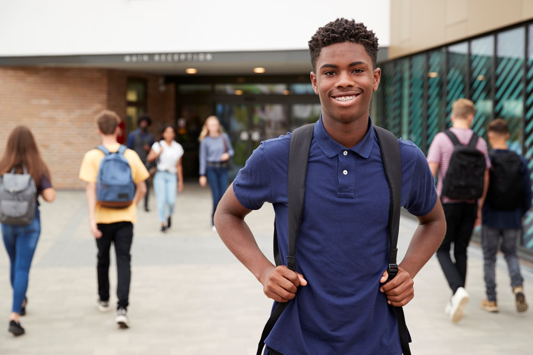 Smiling student stands outside of school building